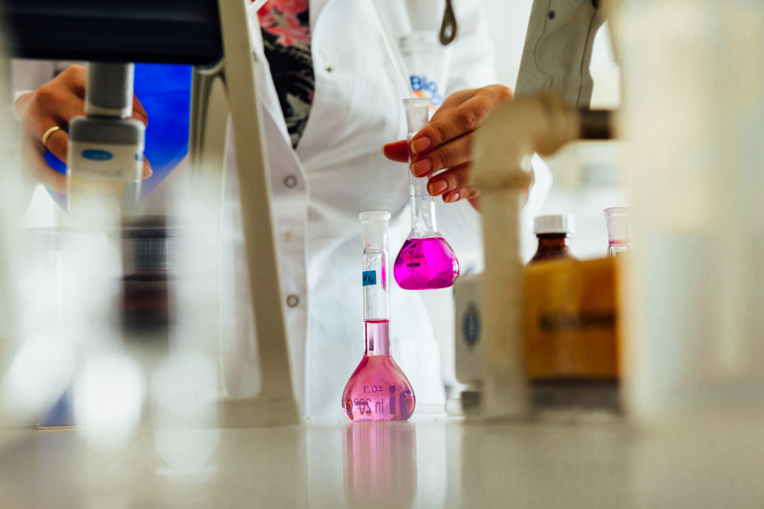Analityk w laboratorium chemicznym z kolbami miarowymi z barwnym roztworem